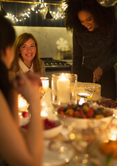 Obraz na płótnie Canvas Smiling friends enjoying candlelight Christmas dessert