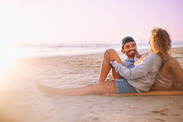 Smiling couple relaxing and talking on sunset beach