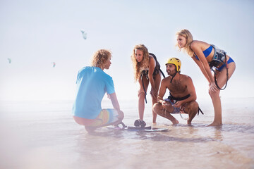Man teaching friends kiteboarding on sunny beach