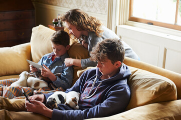 Brothers sister using digital tablet cell phone with puppies in laps