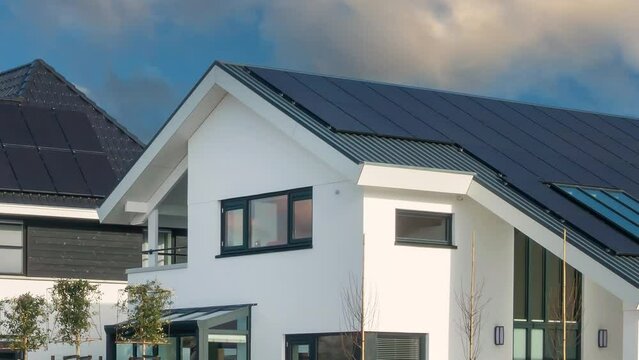 Horizontal pan of newly built Dutch houses with solar panels attached to the roof