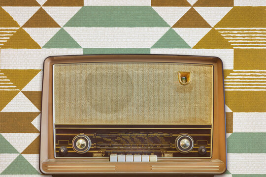 Vintage radio with display showing European cities in front of retro wallpaper
