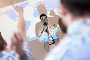 Speaker at projection screen answering questions at technology conference