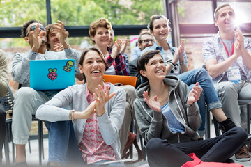 Smiling audience clapping at technology conference