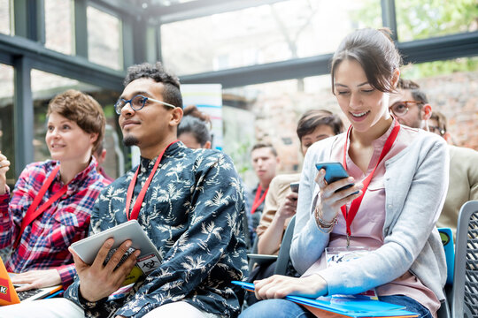Woman texting with cell phone in audience at technology conference