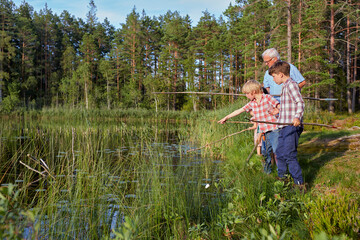 Fototapeta na wymiar Grandfather teaching grandsons fishing at sunny lakeside