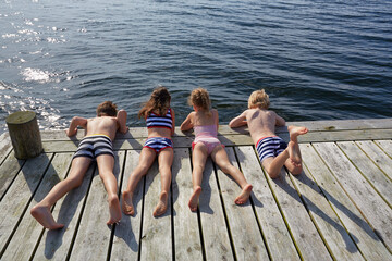 Boys and girls laying on dock looking down at lake