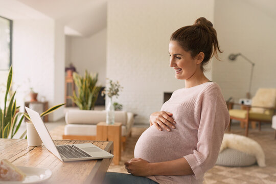 Pregnant woman video conferencing at laptop