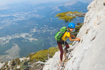 climber goes along the rocky ridge. girl climbing in the mountains. the concept of adventure and hiking in the mountains.