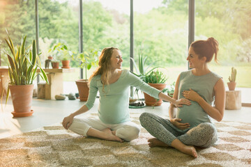 Pregnant women touching stomach in yoga class