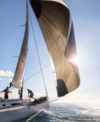 Wind pulling sail on sailboat on sunny ocean - obrazy, fototapety, plakaty