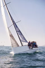 Deurstickers Friends sailing on heeling sailboat on ocean under blue sky © KOTO