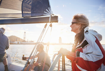Woman sailing steering sailboat at helm on sunny ocean