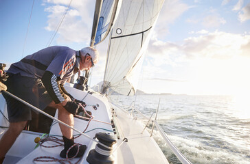 Man sailing pulling rigging on sailboat on sunny ocean - obrazy, fototapety, plakaty