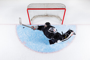 Overhead view hockey goalie reaching to block puck at goal net