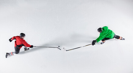 Overhead view hockey opponents reaching for puck on ice