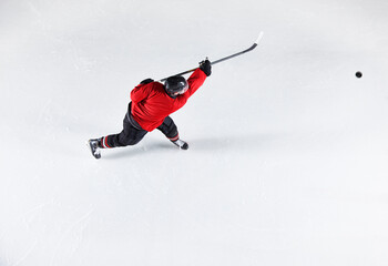 Hockey player in red uniform shooting puck on ice