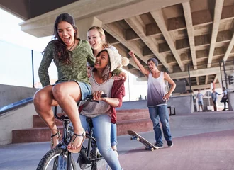 Foto op Aluminium Playful teenage friends riding BMX bicycle skateboarding at skate park © KOTO