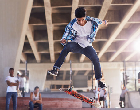 Friends watching teenage boy flipping skateboard at skate park - Powered by Adobe