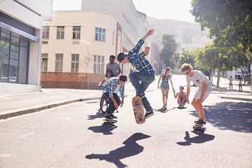 Teenage friends skateboarding on sunny urban street