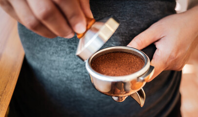 Close-up of hand Barista cafe making coffee with manual presses ground coffee using tamper at the coffee shop