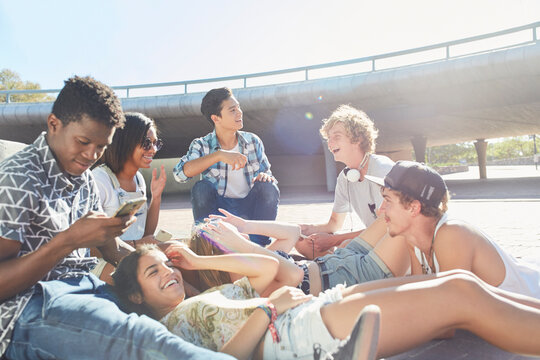 Teenage friends hanging out at sunny skate park
