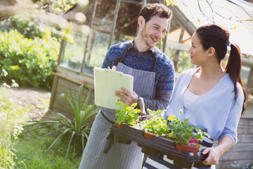 Plant nursery owners with clipboard and potted plants