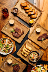 Set of tasty dishes on the table restaurant with beef steak, salad and barbecue chicken wings. Flat lay. Food menu concept