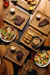 Set of tasty dishes on the table restaurant with beef steak, salad and barbecue chicken wings. Flat lay. Food menu concept