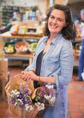 Portrait smiling woman with flowers in basket shopping in market
