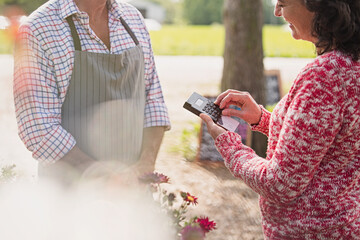 Plant nursery worker waiting as woman uses credit card machine