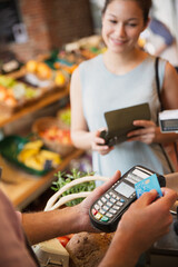 Woman watching grocery store clerk using credit card machine