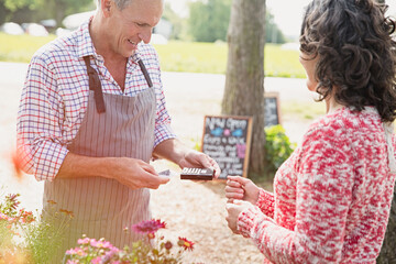 Woman watching plant nursery worker using credit card reader