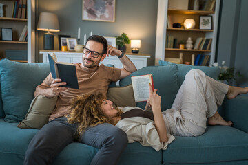 man and woman caucasian adult couple read books at home on sofa bed