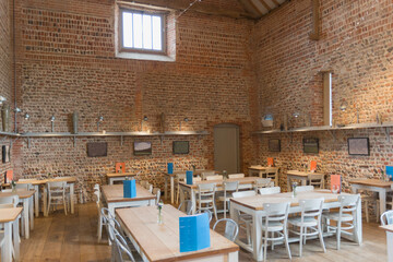 Tables in vacant restaurant with brick walls and vaulted ceiling