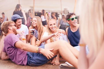 Young friends hanging out drinking and talking at music festival
