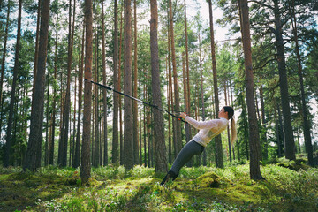 Runner using resistance band on tree in woods