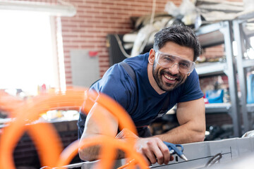 Portrait smiling mechanic working in auto repair shop - obrazy, fototapety, plakaty
