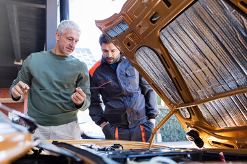 Mechanics checking oil dipstick in auto repair shop