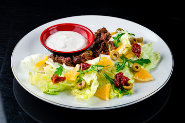 Fried meat with onions and a salad of oranges, sun-dried tomatoes, arugula, olives, lettuce and sauce, shawarma without lavash.