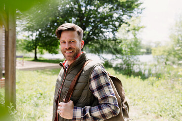 Naklejka na ściany i meble Portrait smiling hiker with backpack in sunny woods