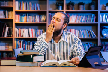 Exhausted young man reading and working at library room