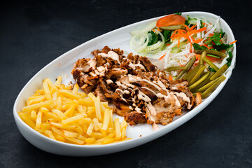 Fried meat with french fries, pickled cucumbers and a salad of cabbage, tomatoes, carrots, onions,...