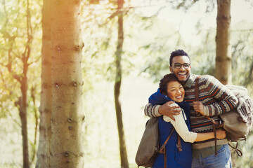 Playful couple with backpacks hugging hiking in woods