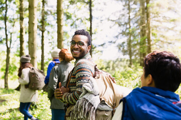 Portrait smiling man with backpack hiking in sunny woods