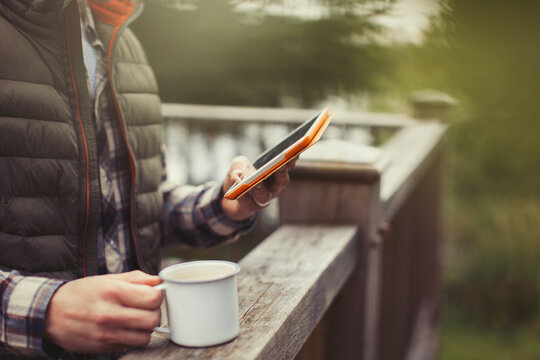 Man drinking coffee using digital tablet on balcony - Powered by Adobe