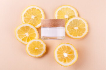 Cosmetic jar with natural energy vitamin skin care. Cosmetic cream qwith slices of lemon on an beige background..