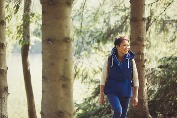 Naklejka na ściany i meble Smiling woman hiking in woods