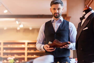 Portrait confident businessman holding dress shoe in menswear shop