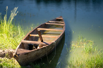 selective focus of wooden object floating on a water- vintage canoe at a river bank
